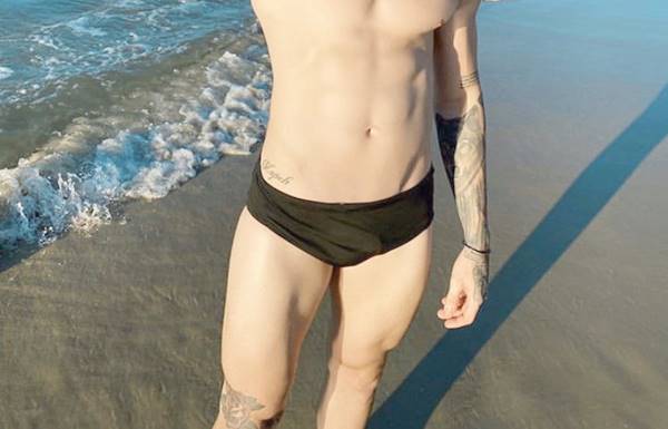 Alex Mapeli na praia de sunga com a pica marcando